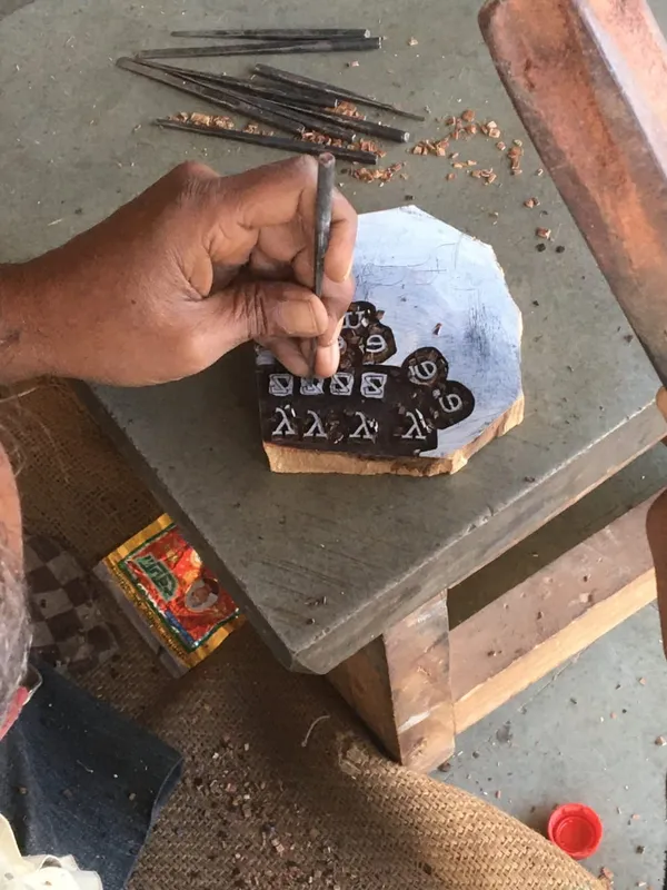 Carving a design into a wooden block with a chisel